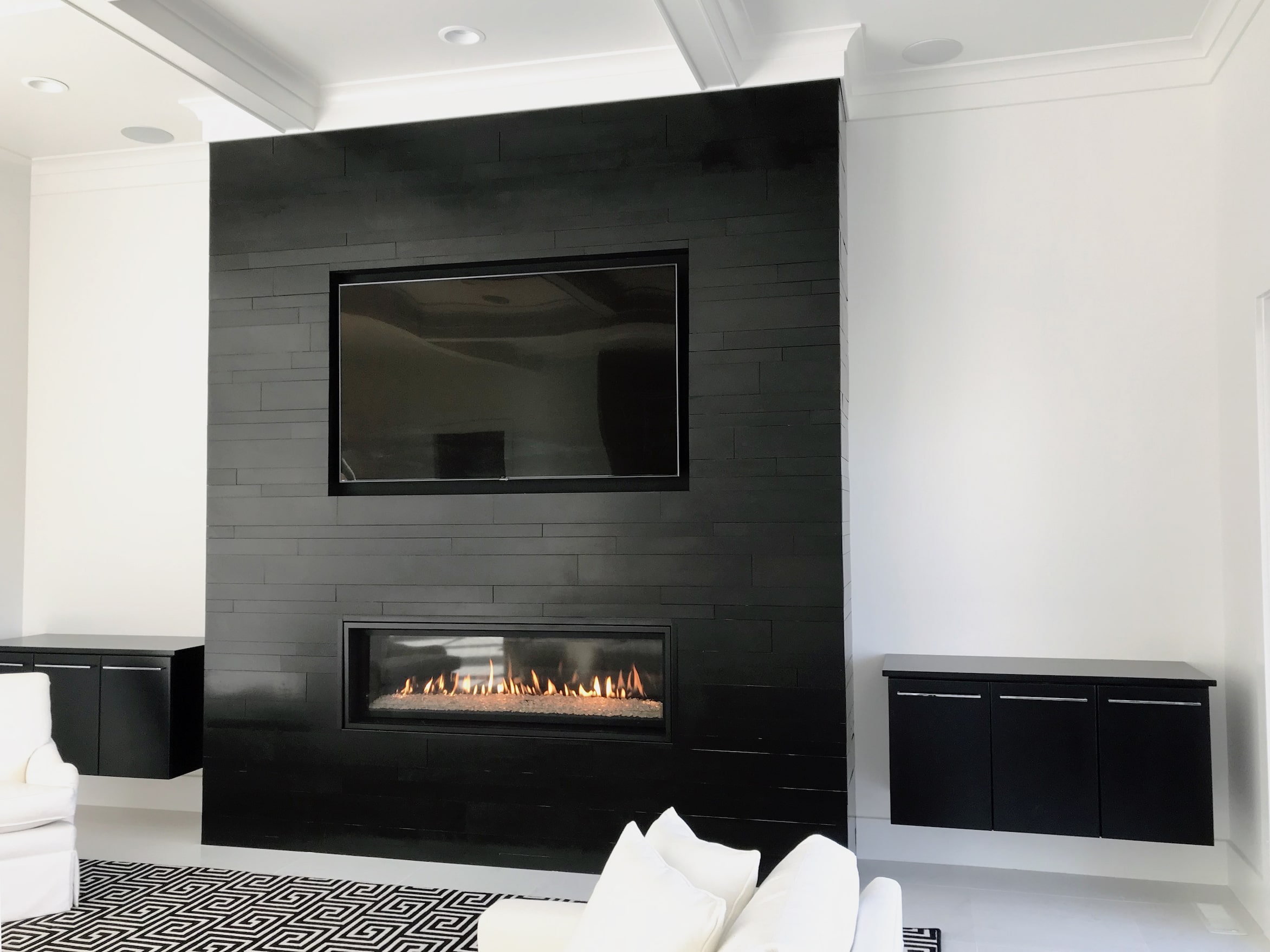 Norstone Planc Large Format Tiles in Ebony installed on a modern fireplace with linear gas insert and tv recess